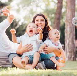 Joyful family enjoying a sunny day in the park while playing with bubbles.