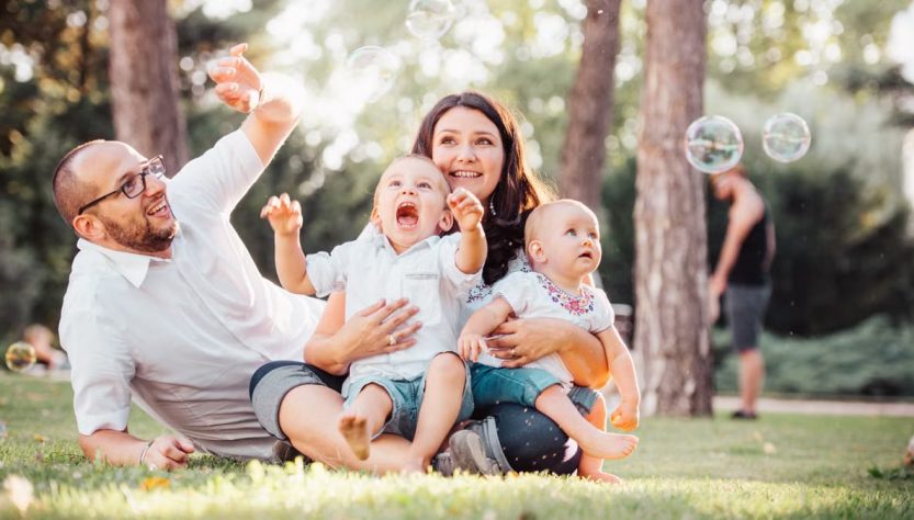 Joyful family enjoying a sunny day in the park while playing with bubbles.